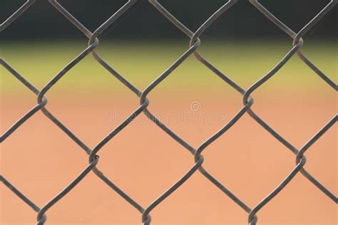 A Close Up Of A Fence At A Baseball Field With The Infield And Outfield