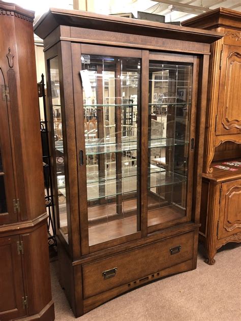 The cabinet is black with a decorative print paper on the back. BROYHILL CURIO CABINET | Delmarva Furniture Consignment