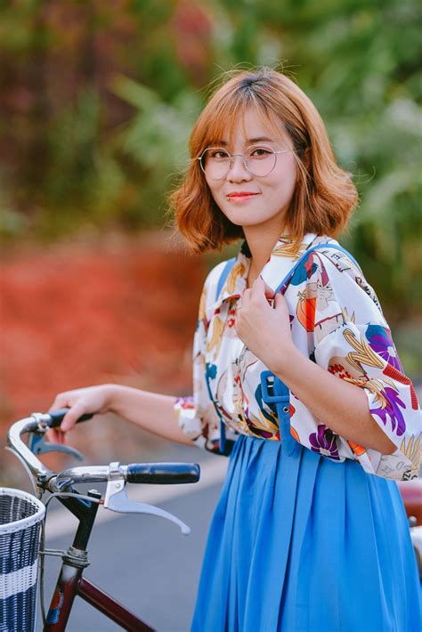A Woman Standing Next To A Bike With Her Hand On The Handlebars