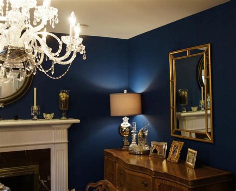 A Living Room With Blue Walls And A Chandelier Hanging Over The Fire Place