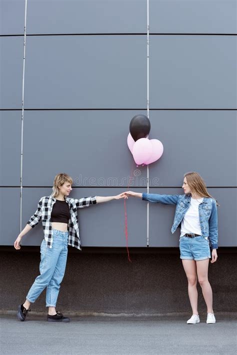 Happy Lesbian Couple Holding Hands With Air Balloons Outdoors Stock