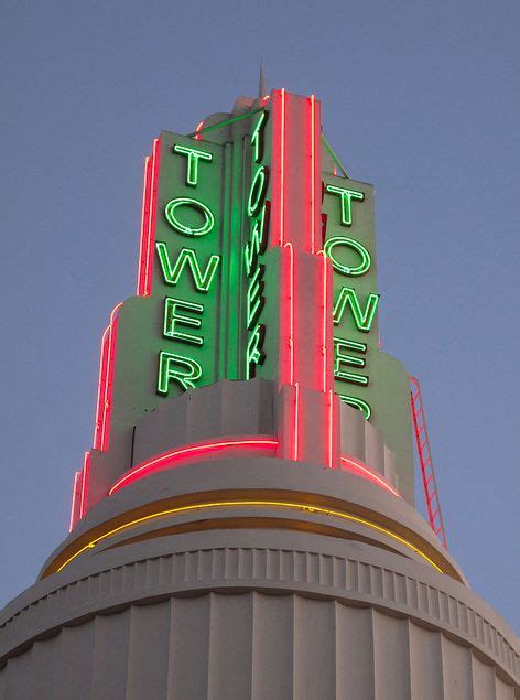 The Top Of A Tower With Neon Signs On It