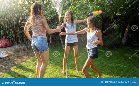Photo Of Three Cheerful Teenage Girls Dancing In The Backyard Garden Udner Garden Water Hose
