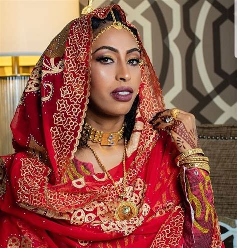 A Woman In A Red And Gold Bridal Outfit Sitting On A Couch With Her Hands Near Her Face
