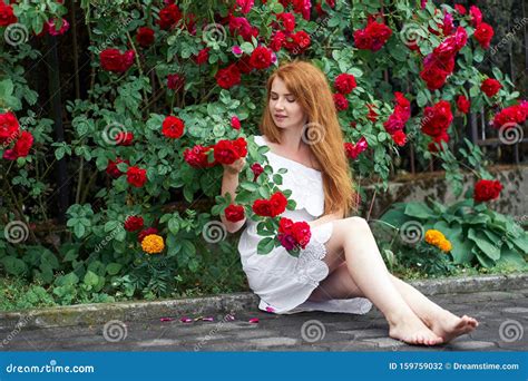 Beautiful Redhead Girl With Bare Feet Wearing In A White Stylish Dress Sitting On Background Of