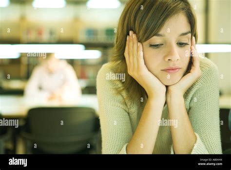 Female College Student Sitting At Table In Library Studying Stock