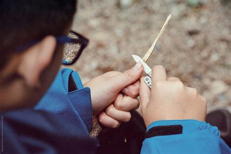 Boy Carving A Stick With A Pocket Knife By Stocksy Contributor