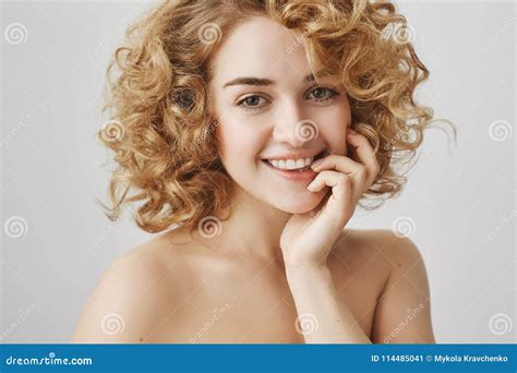 waist up portrait of sensually attractive european woman with short curly hair biting finger