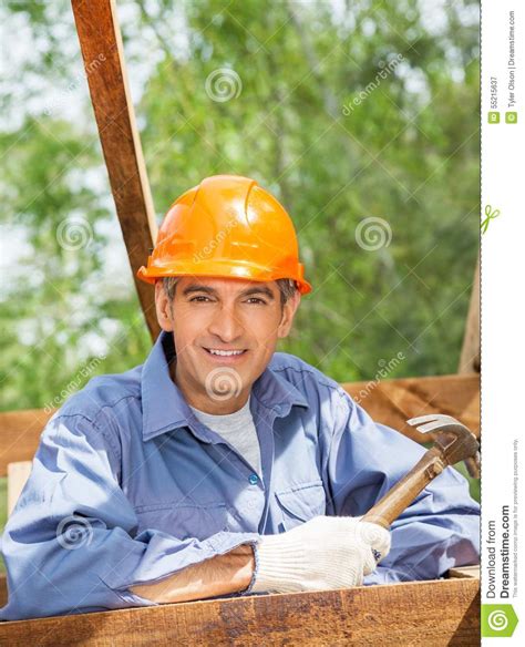 smiling construction worker holding hammer at site stock image image of mature construction