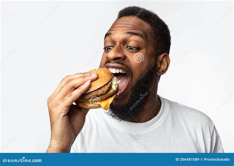 Portrait Of Hungry Black Man Eating Burger Over White Background Stock