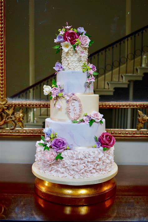 A Three Tiered Wedding Cake With Purple And Pink Flowers On The Top In