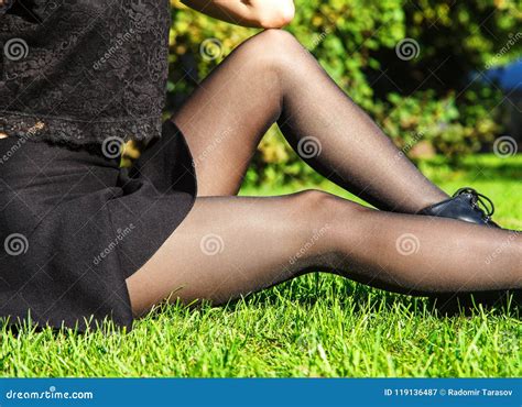 Nogi M Oda Kobieta Siedzi Na Trawie W Czarnych Po Czochach Obraz Stock