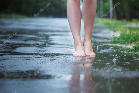 Young Beautiful Girl Walking In The Park In The Summer Warm Rain Barefoot Through The Puddles