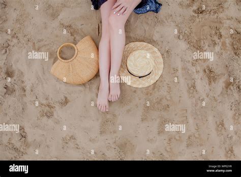 Woman Tanned Legs Straw Hat And Bag On Sand Beach Travel Concept