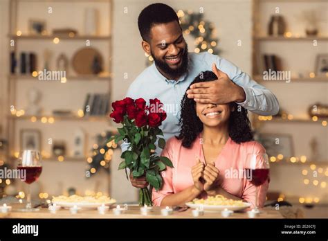 Young Black Man Giving Flowers To Woman Covering Eyes Stock Photo Alamy