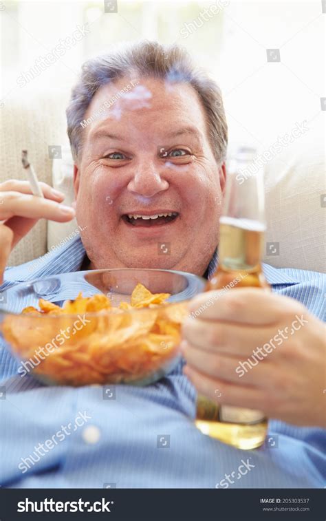 Overweight Man Eating Chips Drinking Beer Foto Stock 205303537