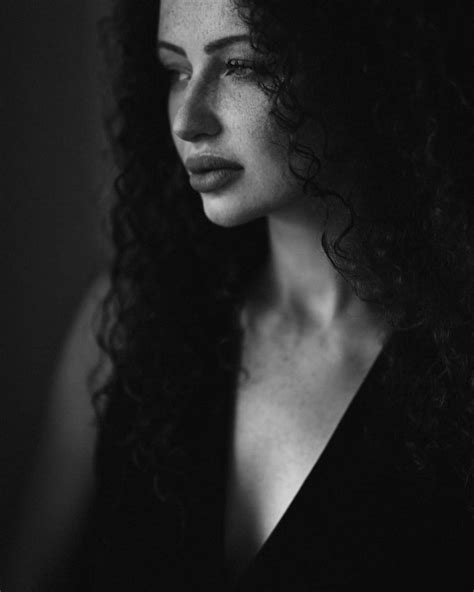 A Black And White Photo Of A Woman With Curly Hair Looking Off To The Side