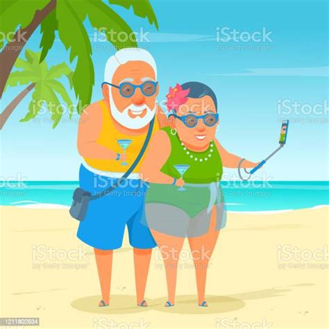 An Active Happy Elderly Couple Standing On Beach Sand Smiling Taking A Selfieshot Sunny Day