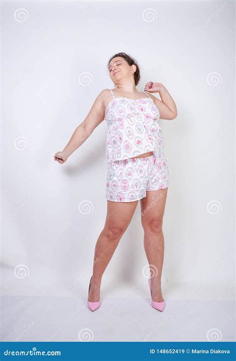 Curvy Chubby Woman In Funny Pajamas Stands And Stretchintg On A White