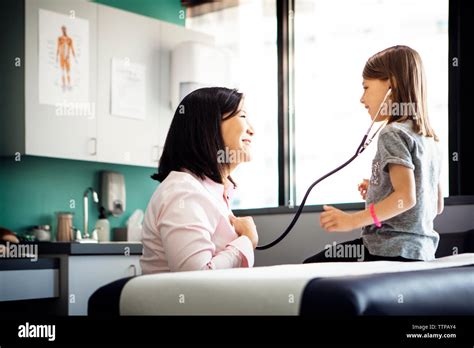 Side View Of Girl Listening To Heartbeat Of Female Doctor Through