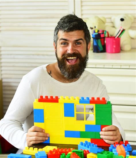 Man With Cheerful Face Makes Brick Constructions For Kids Stock Photo