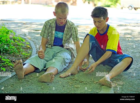 Two Barefoot Boys Sitting On The Ground Stock Photo Alamy