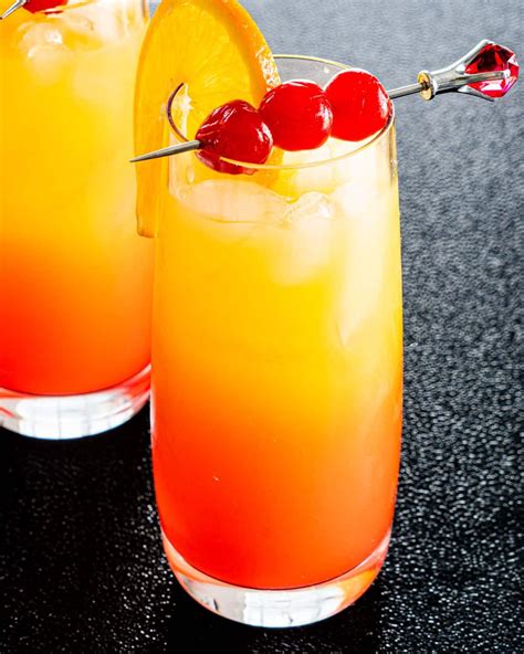Two Glasses With Tequila Sunrise Garnished With Orange And Maraschino Cherries Tequila Sunrise