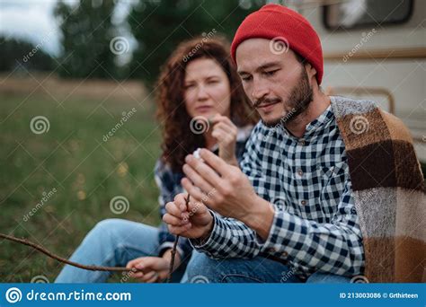 Couple In A Checkered Plaid Roasting Marshmallows On Fire Near The