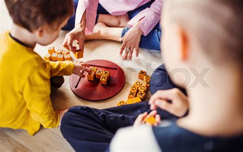 A Midsection Of Mother With Two Children Playing Board Games On The