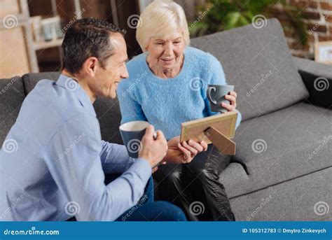 Elderly Woman And Her Son Looking At Framed Photo Stock Image Image