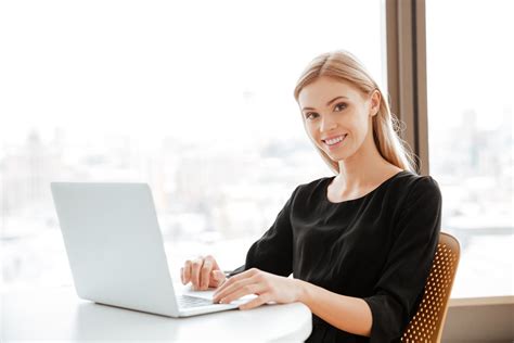 Image Of Happy Young Woman Worker Sitting In Office While Using Laptop