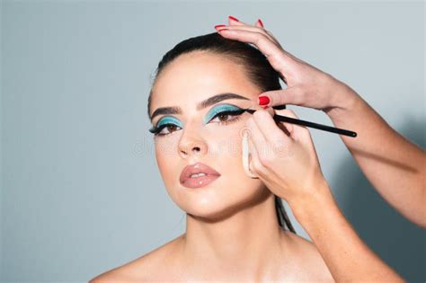 beautiful woman face with perfect makeup makeup artist applies eye shadow hand of visagiste