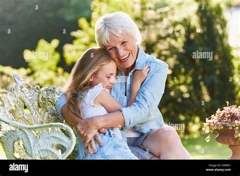 Grandmother And Granddaughter Hugging On Garden Bench Stock Photo Alamy