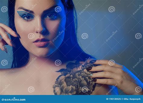 Brunette Girl With A Flower Tattoo On Her Shoulder And Tunnels In Her