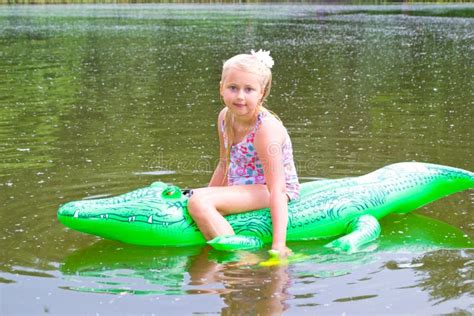 Girl Swimming In The River With Inflatable Crocodile Stock Image