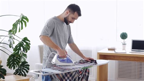 Smiling Dark Haired Male Ironing Attentively Clothes With Vapor Stock