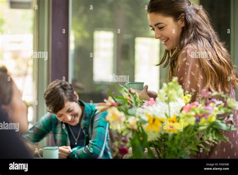 Three Women Talking And Laughing Seated Around A Table Large Bunch Of