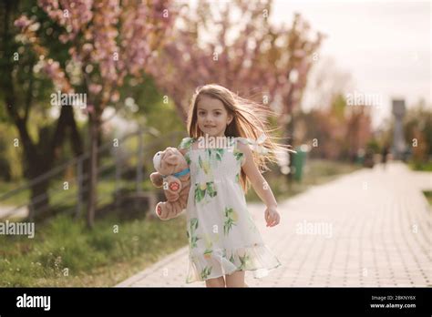Little Girl Walk In The Park Barefoot And Hug Teddy Bear Stock Photo