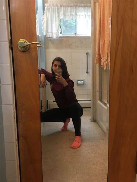 a woman is taking a selfie in the bathroom while sitting on the floor with her feet up