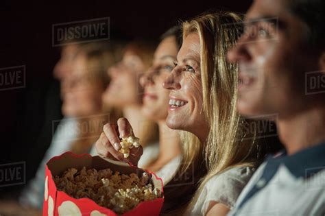 Woman Eating Popcorn While Watching Movie In Theater Stock Photo