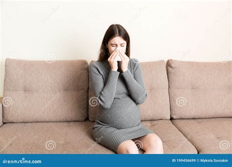 Young Vomiting Woman Sitting On Sofa And Suffering With Nausea