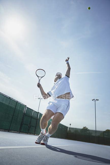 Young Male Tennis Player Playing Tennis Serving The Ball On Sunny
