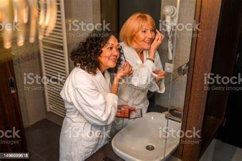 Two Beautiful Mature Women Apply Eye Shadow Together In White Robes