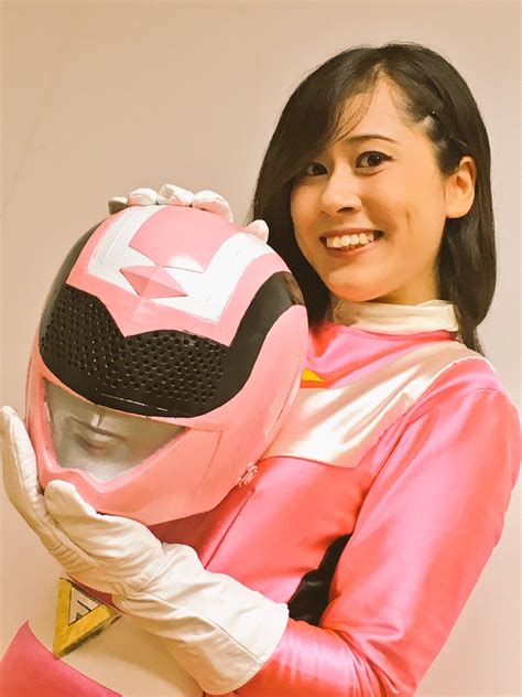 A Woman Wearing A Pink Power Ranger Costume And Holding A Helmet On Her