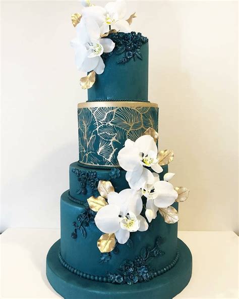 A Three Tiered Blue Cake With White Flowers On Top