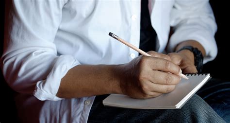 Cropped Shot Of Man Writing On Paper Notebook With Pencil Stock Photo