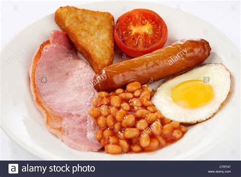 Full english breakfast with bacon, sausage, egg, baked beans and orange juice. Sausage egg bacon beans tomato and hash brownie Stock Photo - Alamy