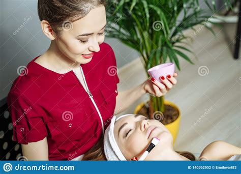 Beautician Applying A Mask On The Face Of A Young Woman Stock Photo