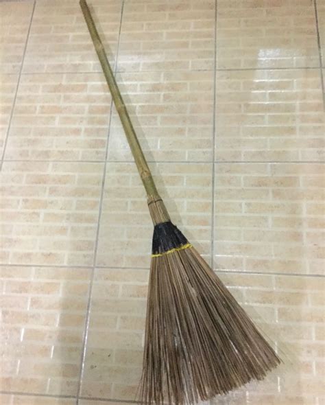 A Broom Laying On The Floor In Front Of A Tiled Wall
