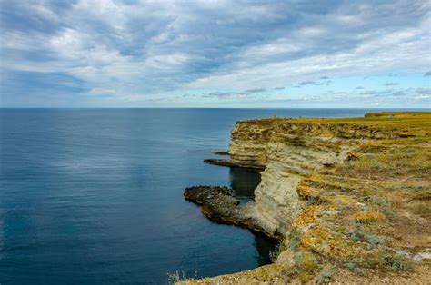 Premium Photo A Rocky Cliff Face With The Ocean In The Background